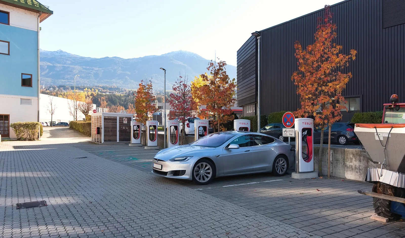 Voiture électrique grise en charge sur une station de recharge rapide avec les montagnes des Alpes en arrière-plan
