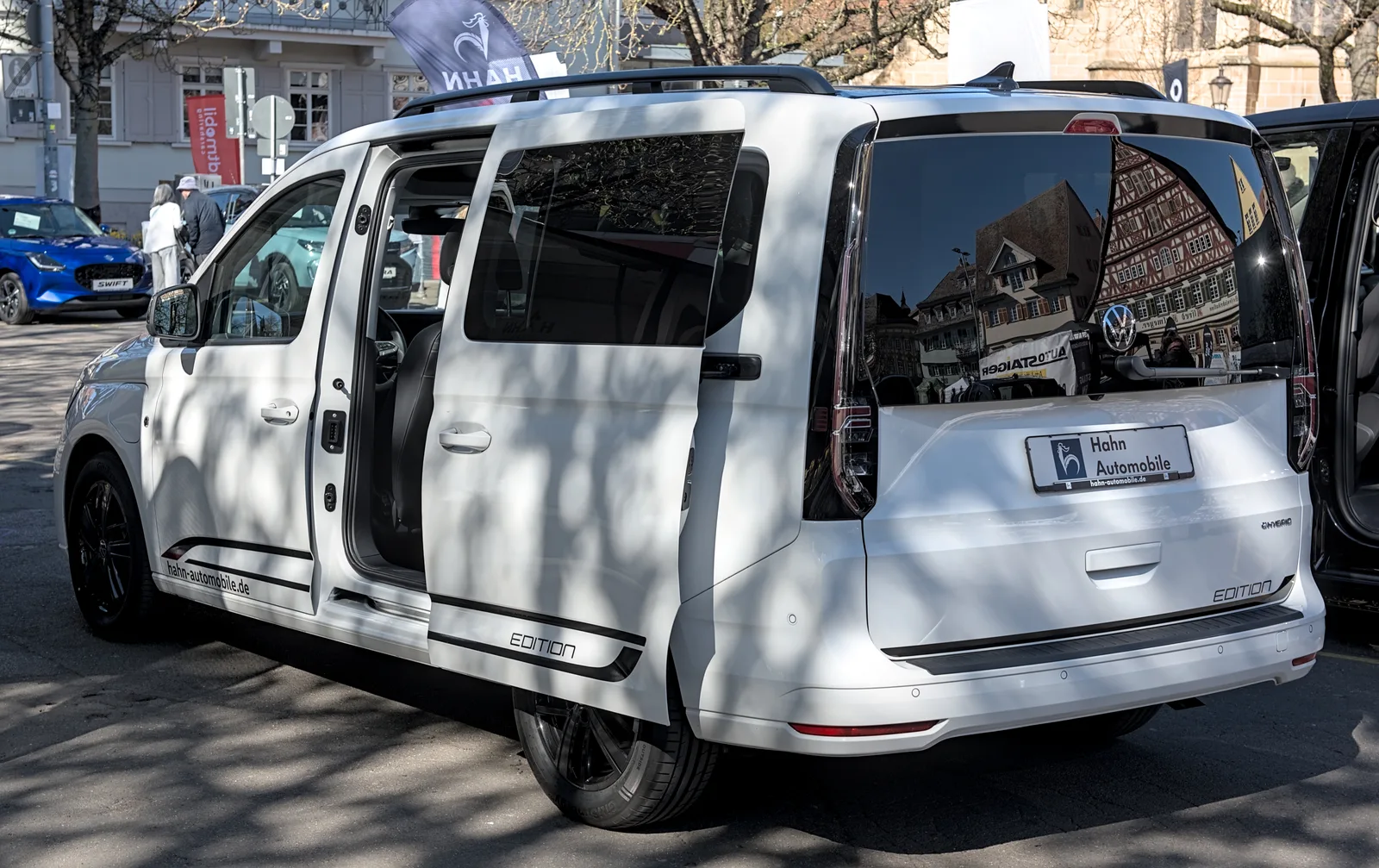 Volkswagen Caddy 2026 vue trois quarts arrière eHybrid blanc portière coulissante ouverte rue