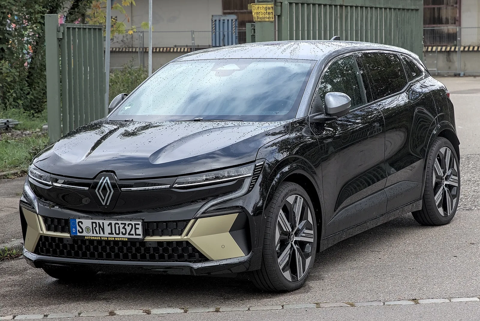 Renault Mégane E-Tech noire vue trois quarts avant garée dans la rue sous la pluie