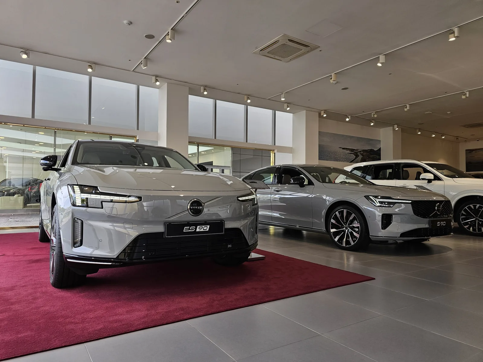 Volvo ES90 2026 exposée dans un showroom Volvo aux côtés d'une S90 grise
